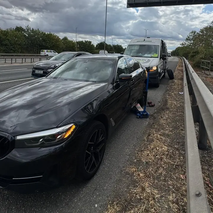 A BMW jacked up on the motorway hard shoulder, the van parked behind it