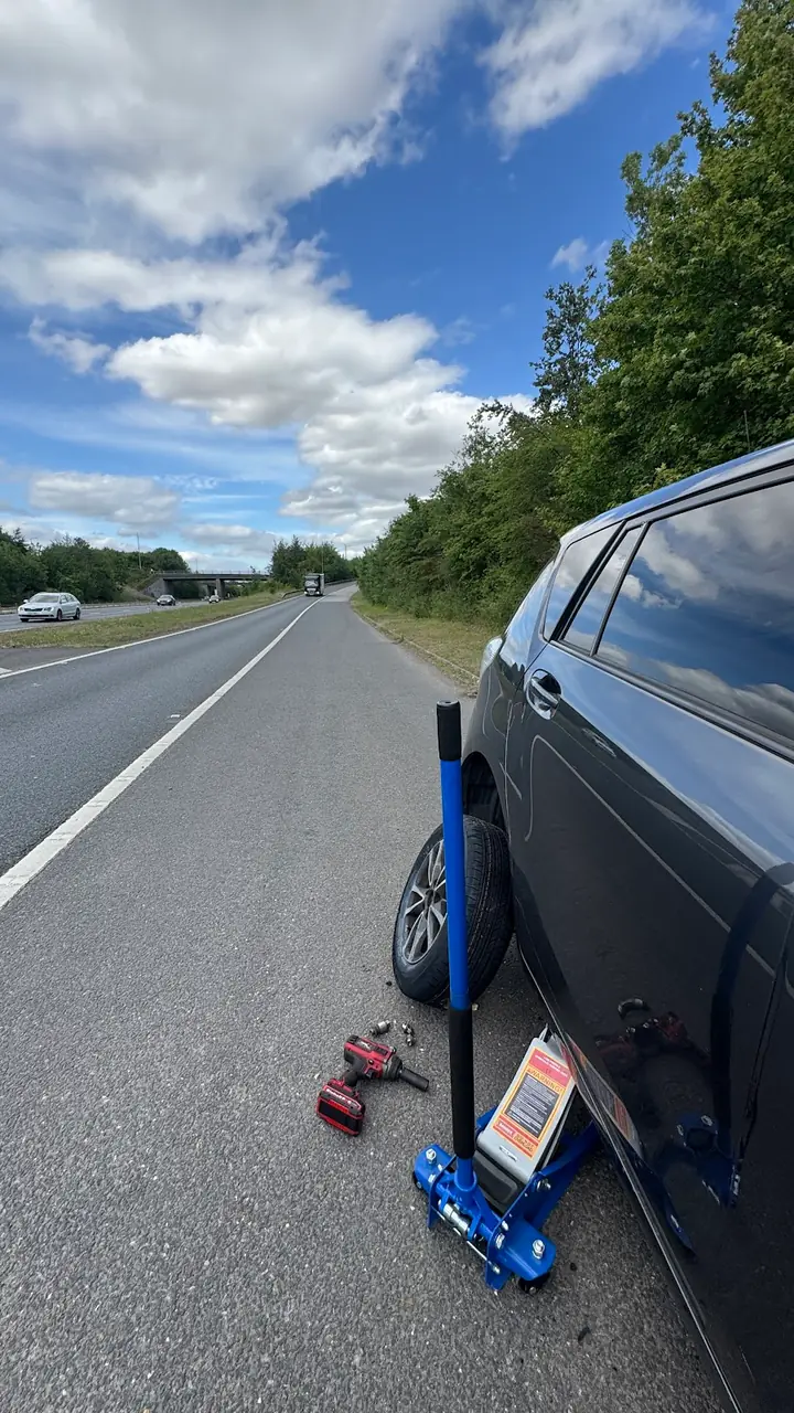 A car jacked up safely on the verge of an A-road for a tyre change